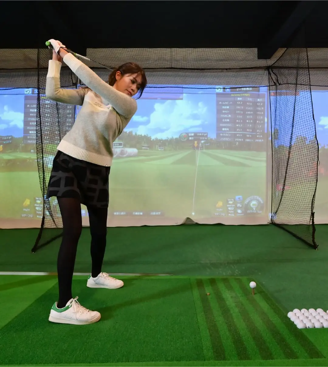 シミュレーションゴルフを使う女性ゴルファーの様子